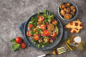 Fototapeta na wymiar Vegetarian salad of leaves, tomatoes, pickled champignon mushrooms. Concept healthy food. Top view, copy space.