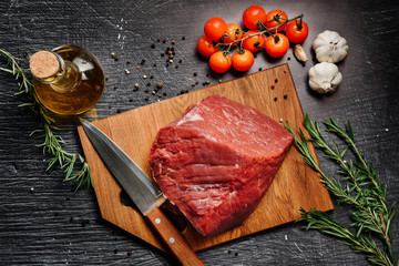 Composition with a piece of raw beef, cherry submidors, branches of rosemary, garlic and olive oil.