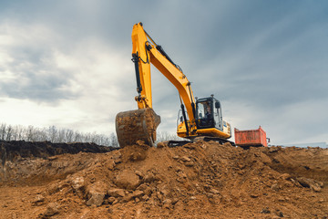Obraz premium A large construction excavator of yellow color on the construction site in a quarry for quarrying. Industrial image