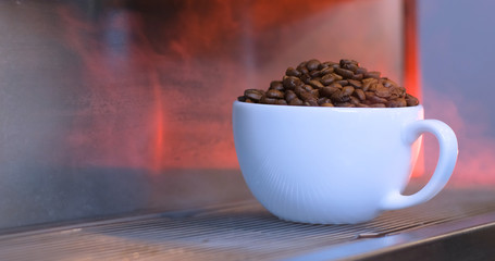 Coffee beans in the porcelain cup. Coffee and color steam.