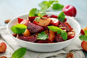 Vegan Plum, beet salad with pecan nuts, mint and herbs in white bowl. healthy summer food.