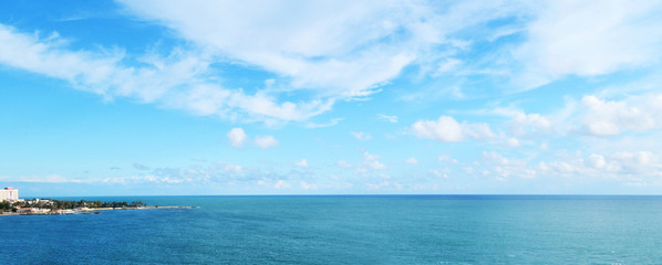 cloudy blue sky leaving for horizon above a blue surface of the sea