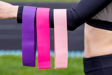 fitness girl holding three fitness gum stretchs (Strong,medium, light) for workout