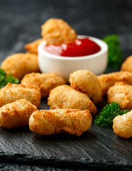 Crispy Battered scampi nuggets with ketchup and mayonnaise on rustic stone board.