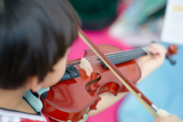 rear view of boy plays violin on blur note background ,selective focus