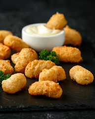Crispy Battered scampi nuggets with ketchup and mayonnaise on rustic stone board.