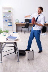Young male employee throwing rugby ball in the office