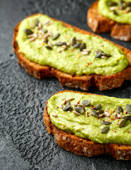 Healthy Homemade Avocado creamy Toast with nuts mix on rustic background