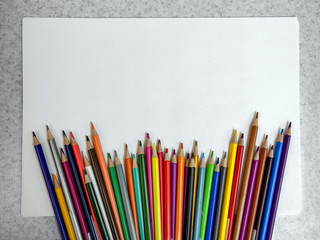 colored pencils lying randomly on the edge of a white sheet of paper