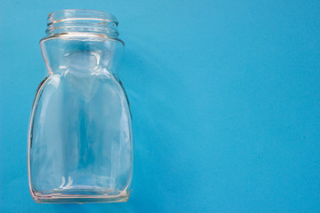 Transparent glass empty bottle on a blue background with place for your design.