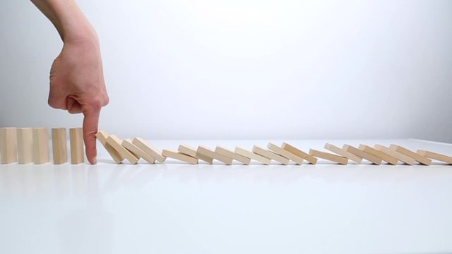 Crisis concept. Businessman stops falling dominoes. Strategy for successfully solving a problem in business. Financial risks.