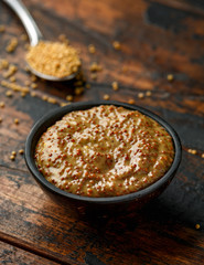 whole grain mustard in bowl on wooden table.