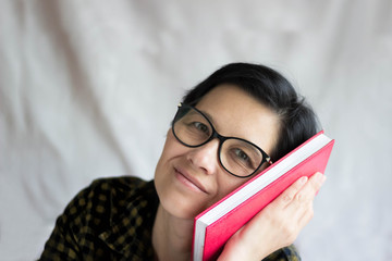 A pretty middle-aged brunette with glasses smiles and looks intriguingly at the camera, her head...