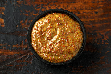 whole grain mustard in bowl on wooden table.