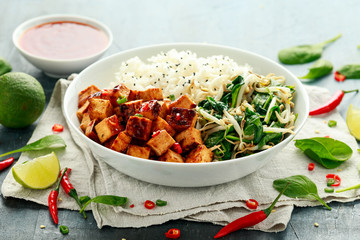 Fried tofu in sweet chilli glaze served with rice, steamed spinach and beansprouts in white bowl. Vegetable healthy food