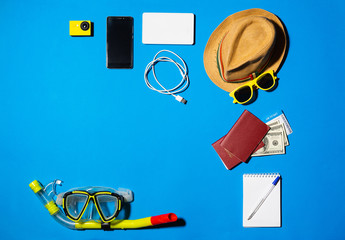 Random travel objects on blue background. Overhead view, flat lay.