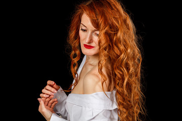 Fototapeta premium Beautiful girl with red hair in a white shirt and a hat on a black background