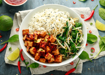 Fried tofu in sweet chilli glaze served with rice, steamed spinach and beansprouts in white bowl. Vegetable healthy food