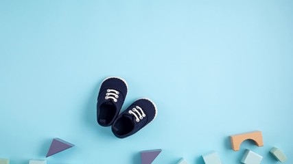 Cute newborn baby boy shoes with festive decoration over blue background. Baby shower, birthday, invitation or greeting card idea