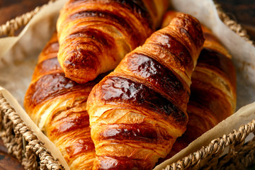Freshly baked croissants with butter in wooden tray