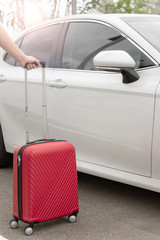 The concept of traveling by vehicle. Transfer. Cardsharing. hand holding the red suitcase next to a...