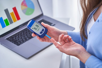 Diabetic patient checks blood glucose level using glucometer. Diabetes control and healthcare. Studying and examining glucose graphs on a computer online