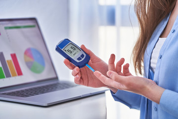 Woman diabetic patient checks blood glucose level using glucometer. Diabetes control and examining...