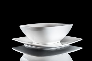 White round plate for food on dark background. Empty dishes for dinner isolated on black. Restaurant kitchen minimalistic concept.