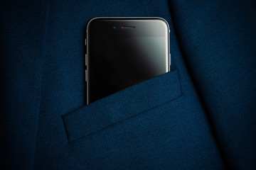Black smartphone in men suit pocket close up.