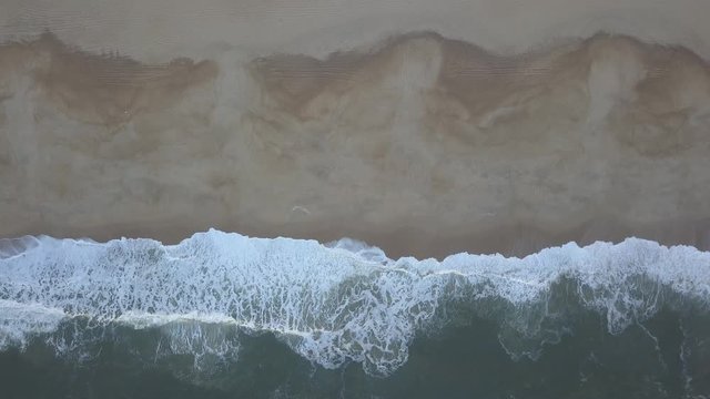 Flying over a sandy beach. Waves break on a sandy beach on the Atlantic coast, aerial View. Nazare, Portugal. (raw video).