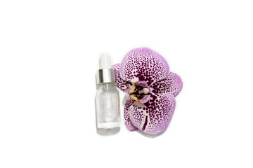 A cosmetic bottle and beautiful purple orchid isolated on the white background. Nature cosmetics concept.