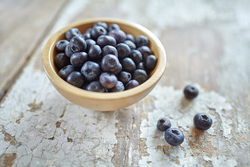 Image of blueberries in wooden bowl on rustic village table.