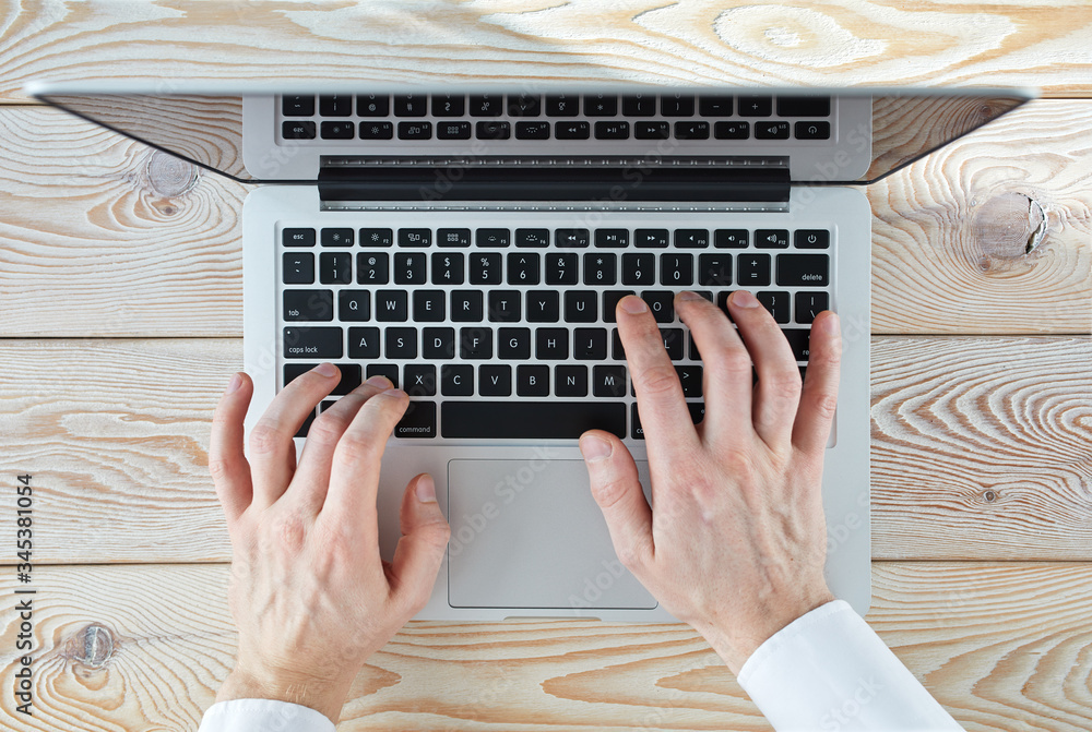 Poster top view of man's hands typing on laptop in sunny day. coworking or working at home concept image.