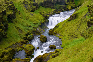 Fototapeta na wymiar Skogar river flows between green hills, nature of Iceland