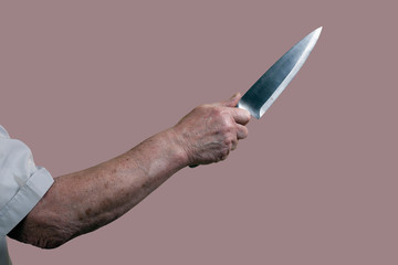 The hand of an elderly man with a knife. Isolate on a brown background. The concept of threat to...