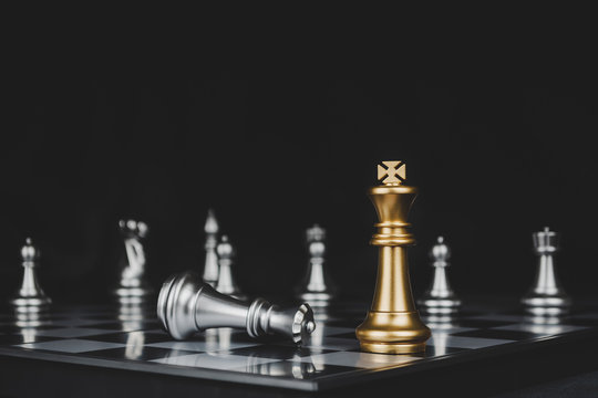 Winner. gold king surrounded with silver chess pieces on chess board game competition with copy space on dark background, chess battle, success, team leader, teamwork and business strategy concept