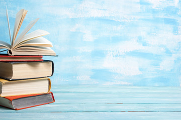 Composition with vintage old hardback books, diary, fanned pages on wooden deck table and red background. Books stacking. Back to school. Copy Space. Education background.