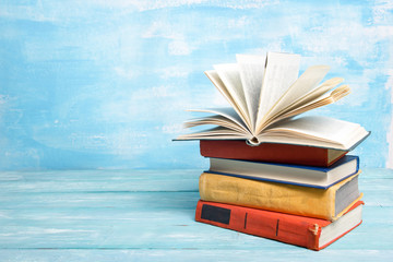 Composition with vintage old hardback books, diary, fanned pages on wooden deck table and red background. Books stacking. Back to school. Copy Space. Education background.