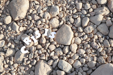 The word CRISIS in paper letters on the background of stones. Crisis concept.
