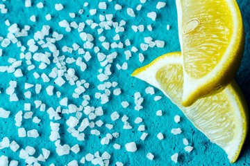 white crystals of coarse salt and lemon on blue background