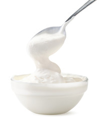 Sour cream flows from a spoon in a bowl on a white background. Isolated