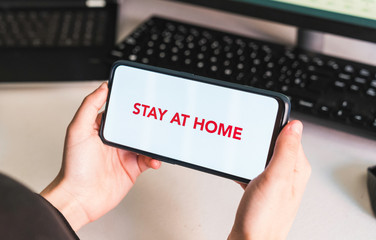 Stay at home. Put your message on the phone. Hands of a woman holding a mobile phone with a blank screen to put a text message or advertising content. Social distance. Coronavirus devices.