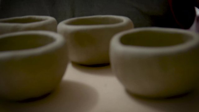 Eine Frau, Handwerkerin und T&ouml;pferin, tr&auml;gt mehrere get&ouml;pferte Schalen aus Ton zum Brennofen