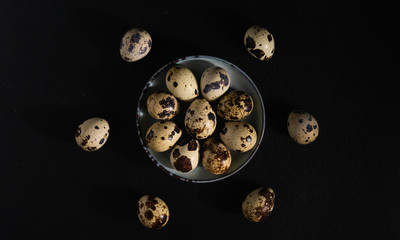 still life, quail eggs on a plate on a dark background, top view