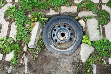 The old wheel from the car serves as a cover for the sewer opening