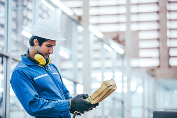 Caucasian mechanic engineer man using equipment to control machine in industrial factory. technician male wearing protective hardhat and uniform working in technology invention industry manufacturing