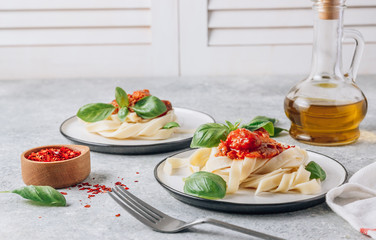 Pasta Tagliatelle Bolognese with meat tomato sauce and fresh basil leaves on white plate. Light gray table.