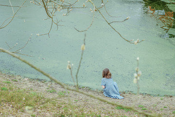 
Little girl in a woolen dress near a small lake in spring