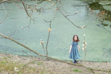 
Little girl in a woolen dress near a small lake in spring