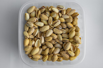 Top view of delicious crispy snack such as salted dry pistachio nuts which is stored in plastic transparent containers, closeup view